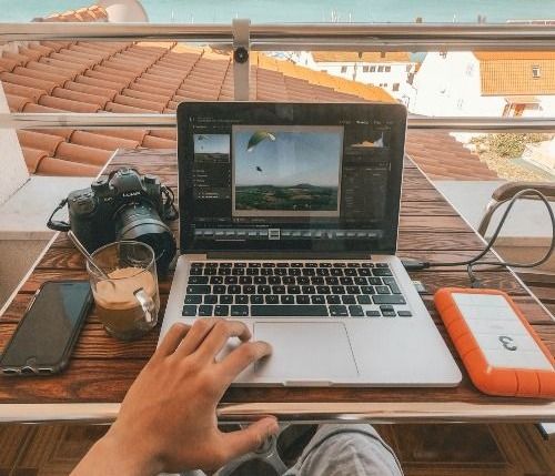 person holding MacBook Pro besides orange power bank